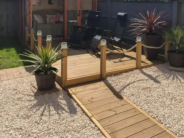Newly built timber garden decking with rope balustrades and solar post lights