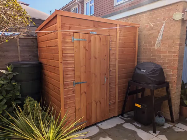 Brand new wooden shed built against a brick wall in a residential garden